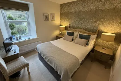 a bedroom with a large bed and a window at Ravenstone Lodge Country House Hotel in Keswick