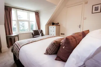 a bedroom with a bed and a chair and a window at Ravenstone Manor in Keswick