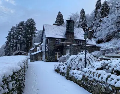 a house covered in snow in front of a yard at Ravenstone Manor in Keswick