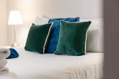 a white bed with two green pillows on it at Elliot Suite No2 - Donnini Apartments in Ayr