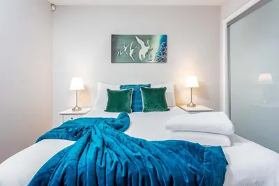 a bedroom with a large bed with a blue blanket at Elliot Suite No2 - Donnini Apartments in Ayr