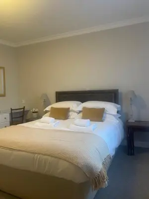 a bedroom with a large bed with white sheets and pillows at The Garret Hotel in Kirkcudbright