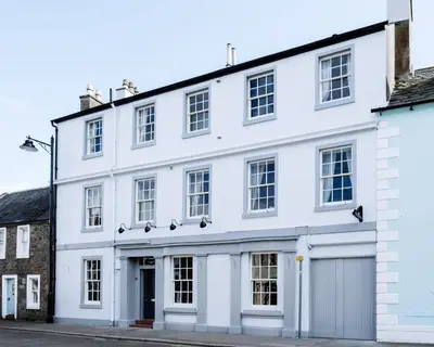 a white building with a garage on a street at The Garret Hotel in Kirkcudbright