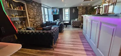 a bar with a row of leather chairs in a room at The Birchtree Hotel in Dalbeattie