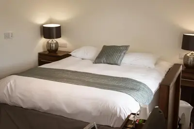 a bed in a bedroom with two night stands and two lamps at The Birchtree Hotel in Dalbeattie