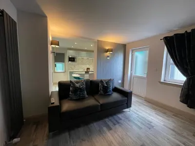 a living room with a brown couch and a window at Apartments No. 19 in Portpatrick