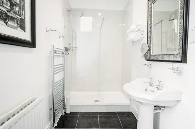 a white bathroom with a sink and a shower at The Town House in Douglas