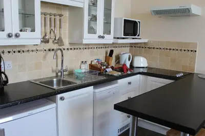 a kitchen with white cabinets and a sink at The Town House in Douglas
