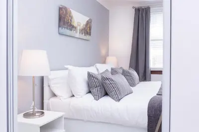 a living room with a white couch with pillows at Peebles House - Coorie Doon Apartments in Ayr