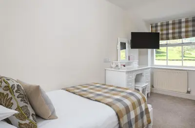 a bedroom with a bed and a desk and a television at The King's Head in Thirlmere
