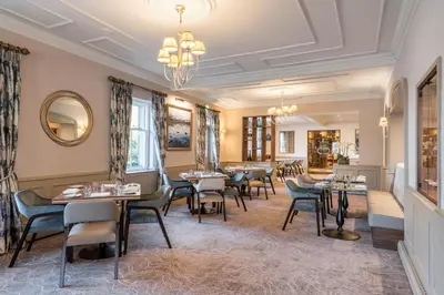a restaurant with tables and chairs and a chandelier at The Borrowdale Hotel in Keswick