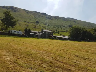 a field with a house in the middle of a hill at Shepherds hut Dolly wagon in Keswick