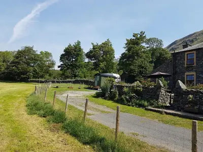 a house with a fence next to a road at Shepherds hut Dolly wagon in Keswick
