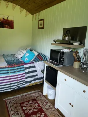 a small bedroom with a bed and a microwave at Shepherds hut Dolly wagon in Keswick