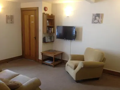 a living room with two chairs and a flat screen tv at Dale Head Hall Lakeside Hotel in Keswick