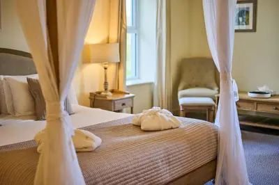 a bedroom with a bed with curtains and a chair at Comis Hotel & Golf Resort in Douglas