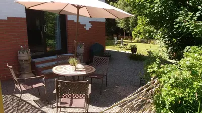 a patio with a table and chairs and an umbrella at Doonbank Cottage Bothy in Ayr