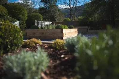 a garden with a stone wall and some bushes at The Grand at Grasmere in Grasmere