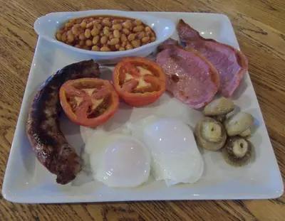 a plate of food with eggs bacon tomatoes and beans at The Old Ginn House Inn in Great Clifton