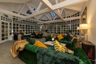 a living room with green couches and a dog laying on a couch at Sella Park Country House Hotel in Seascale