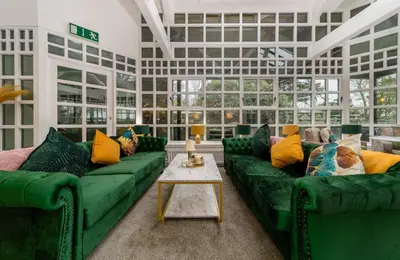 a living room with green couches and a table at Sella Park Country House Hotel in Seascale