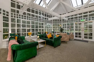 a large living room with green furniture and windows at Sella Park Country House Hotel in Seascale