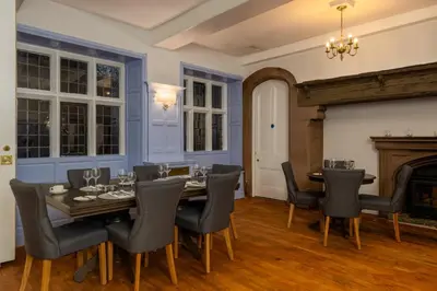 a dining room with a table and chairs and a fireplace at Sella Park Country House Hotel in Seascale