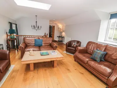 a living room with leather couches and a coffee table at Bracken Holiday Cottage in Dalbeattie