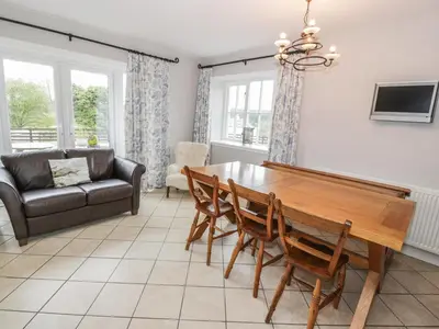 a living room with a wooden table and chairs at Bracken Holiday Cottage in Dalbeattie