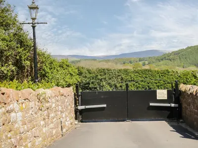 a gate with a stone wall and a street light at Coombs View in Low Hesket