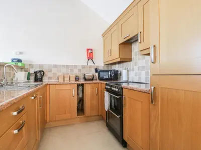 a kitchen with wooden cabinets and a black appliance at Esthers Barn in Cockermouth