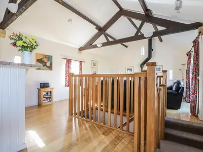 a living room with a wooden staircase in a house at Esthers Barn in Cockermouth