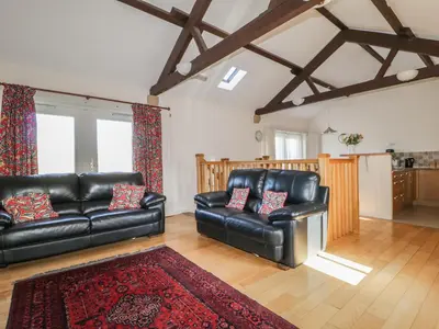 a living room with black leather furniture and a red rug at Esthers Barn in Cockermouth