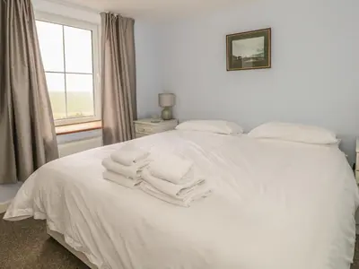 a bedroom with a white bed with towels on it at 2 Park Nook Close in Waberthwaite
