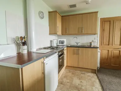 a kitchen with wooden cabinets and a counter top at 2 Park Nook Close in Waberthwaite