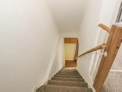 a staircase in a house with a wooden handrail at 2 Park Nook Close in Waberthwaite