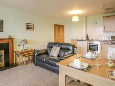 a living room with a leather couch and a table at 2 Park Nook Close in Waberthwaite