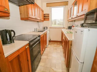 a kitchen with wooden cabinets and a white refrigerator at 1 Park Nook Close in Waberthwaite