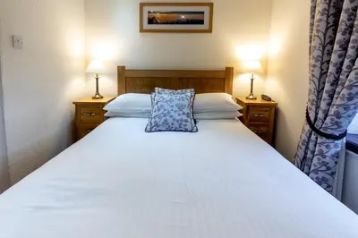 a bedroom with a white bed with a blue pillow at The Britannia Inn in Elterwater