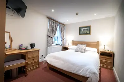 a bedroom with a bed and a desk and a television at The Britannia Inn in Elterwater