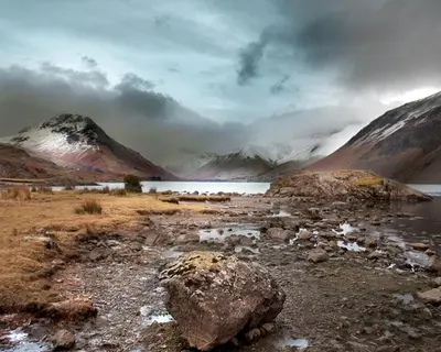 a large rock on a field with a lake and mountains at Strands Hotel/Screes Inn & Micro Brewery in Nether Wasdale