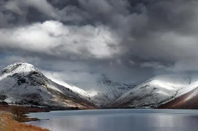 a snow covered mountain with a lake in front of it at Strands Hotel/Screes Inn & Micro Brewery in Nether Wasdale