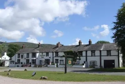 a large white and black building with a building at Strands Hotel/Screes Inn & Micro Brewery in Nether Wasdale