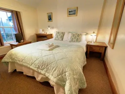 a bedroom with a large bed with two night tables at Strands Hotel/Screes Inn & Micro Brewery in Nether Wasdale