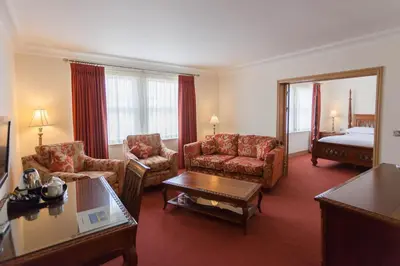 a hotel room with a living room with a bed at Woodland House Hotel in Dumfries