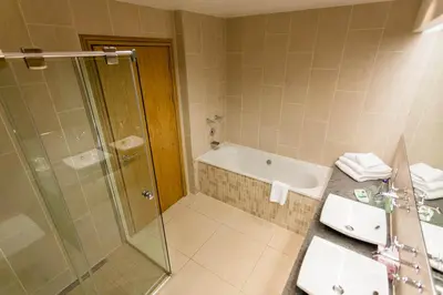 a bathroom with a tub and a sink and a shower at Woodland House Hotel in Dumfries