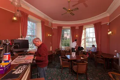 an older man standing in a restaurant at Woodland House Hotel in Dumfries