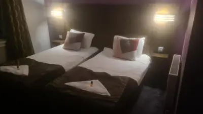 two beds in a hotel room with a candle on them at The Queensberry Hotel in Dumfries