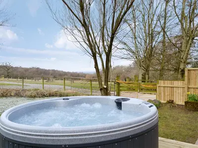 a hot tub in a yard with a tree at Farmhouse Cottage - Uk1285 in Westward