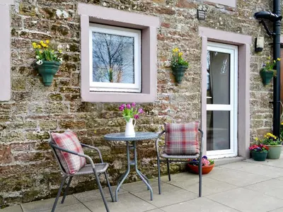 a patio with two chairs and a table and a window at Farmhouse Cottage - Uk1285 in Westward